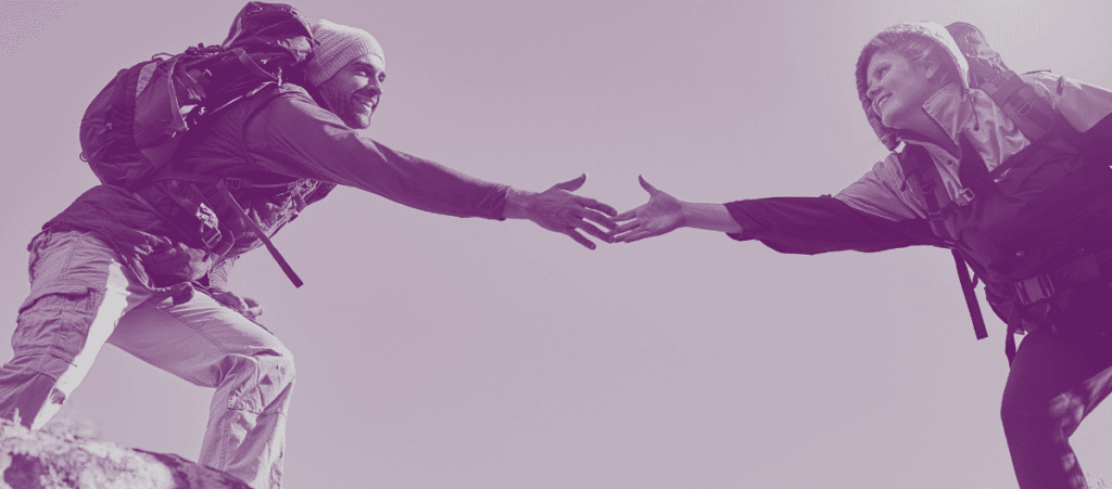 Image of hiker reaching out hand to help another hiker cross a rock gap to illustrate Why Trust Matters & How To Build Trust blog by Lodestar Marketing Group