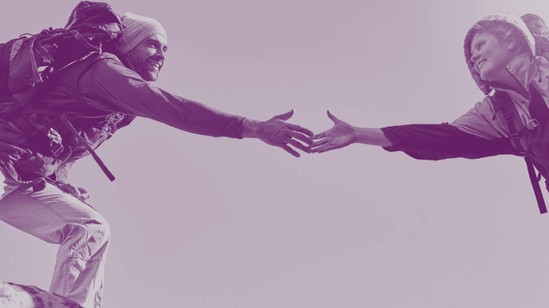 Image of hiker reaching out hand to help another hiker cross a rock gap to illustrate Why Trust Matters & How To Build Trust blog by Lodestar Marketing Group